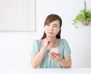 困っていてスマートフォンで何かを調べている女性